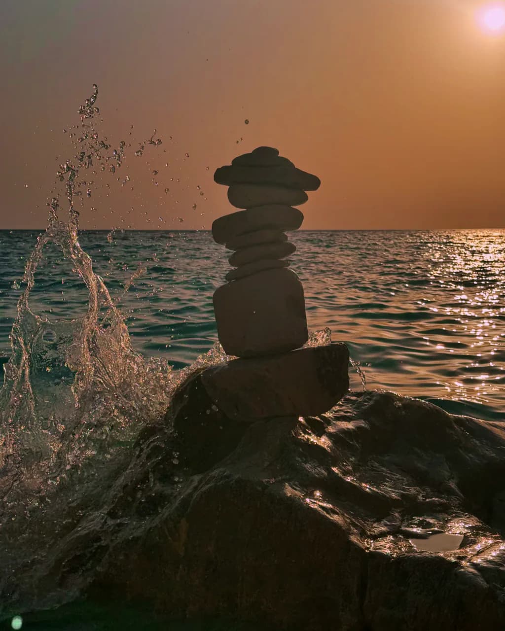 A stack of stones beside the sea at sunset